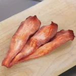Three strips strongly resembling bacon in colour and shape, but tapered at one end, like sliced parsnip.