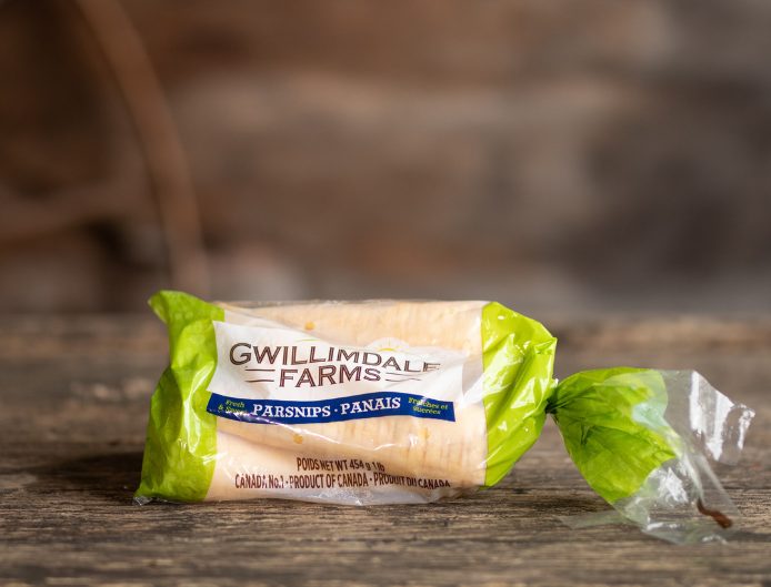 1lb Bag of Gwillimdale Farms Parsnips, resting on an a rustic raw wood table.